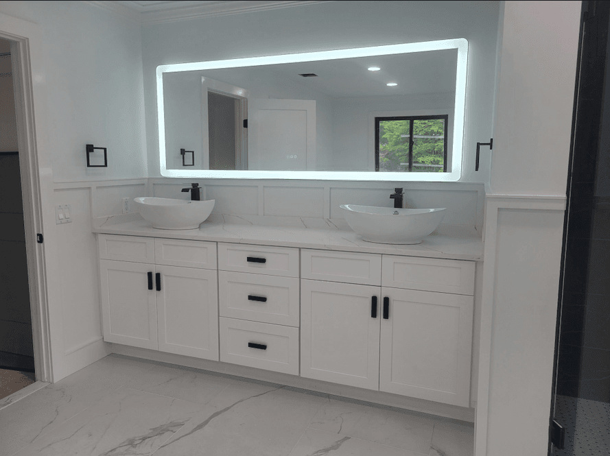 Bathroom double vanity with white cabinetry, vessel sinks and a backlit LED mirror