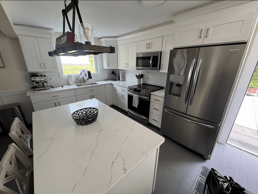 White shaker kitchen with a marble-look quartz island and stainless appliances