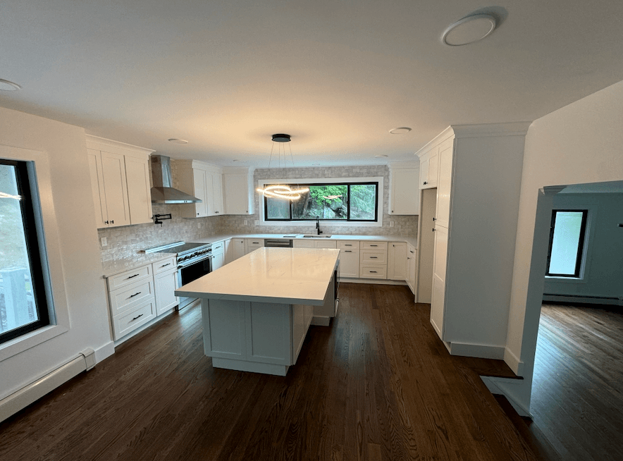 Open kitchen with a center island, white cabinets and wide-plank flooring