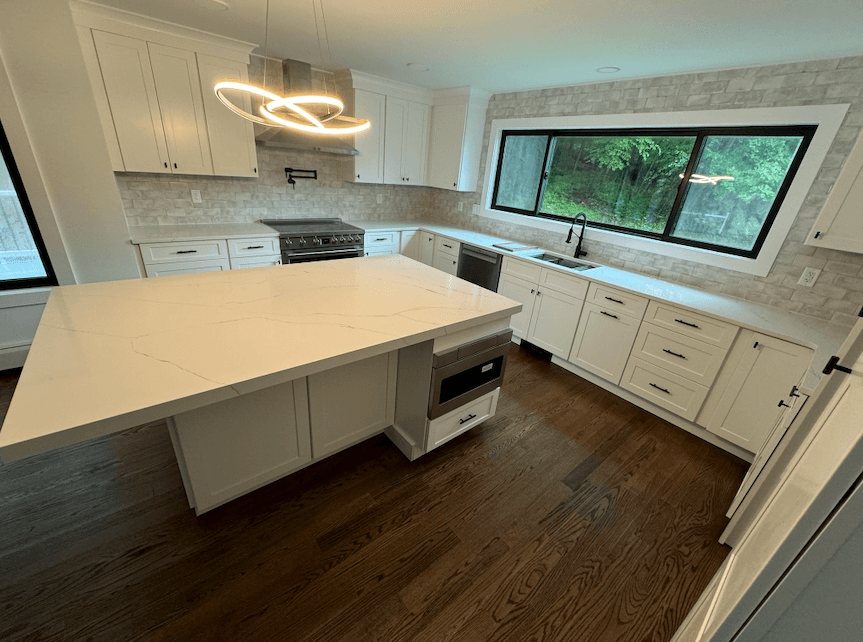 Kitchen island with quartz waterfall end beneath a large picture window